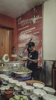 man in black and red crew neck t-shirt holding chopsticks