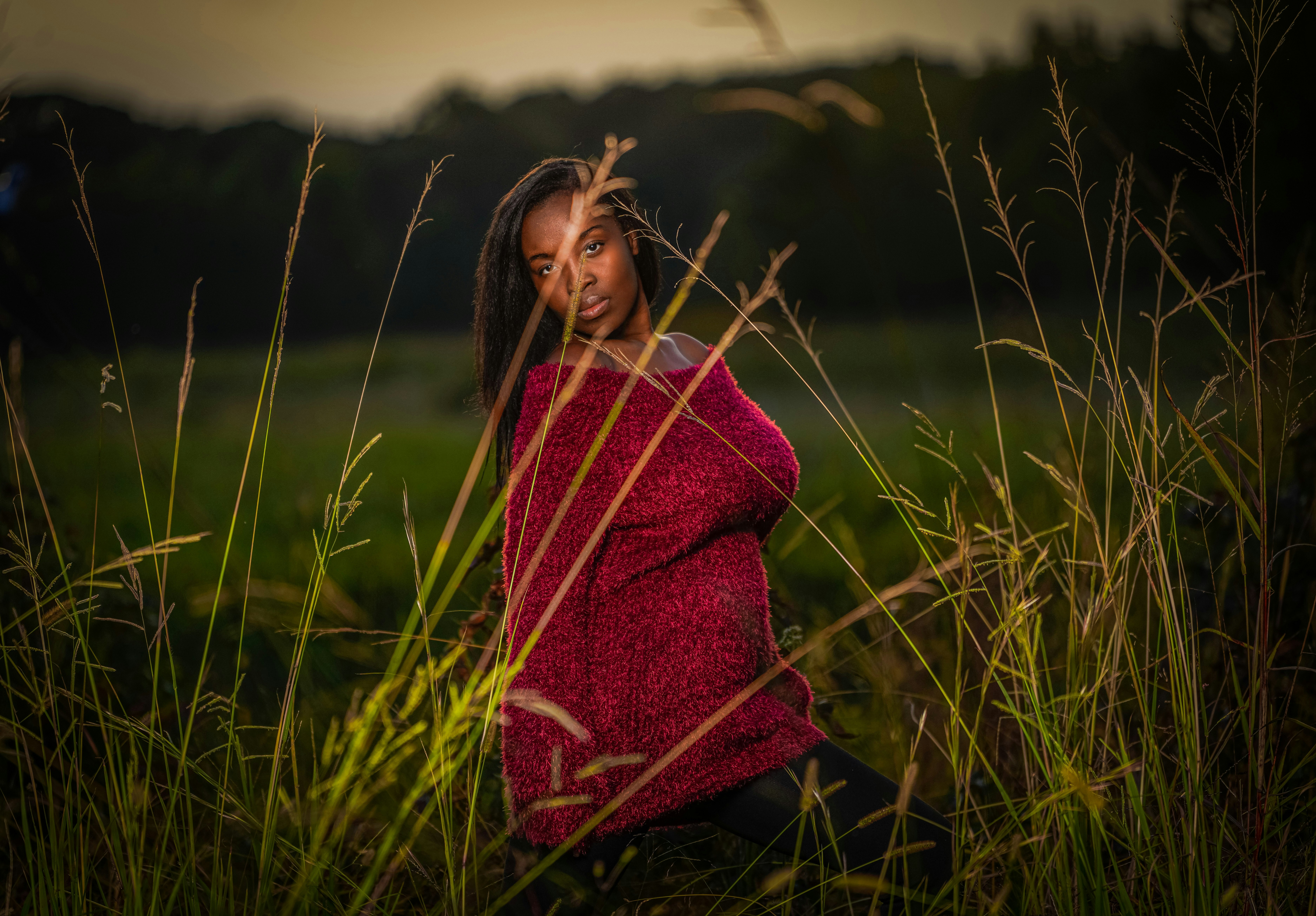 mulher no lenço vermelho e preto em pé no campo de grama verde durante o dia