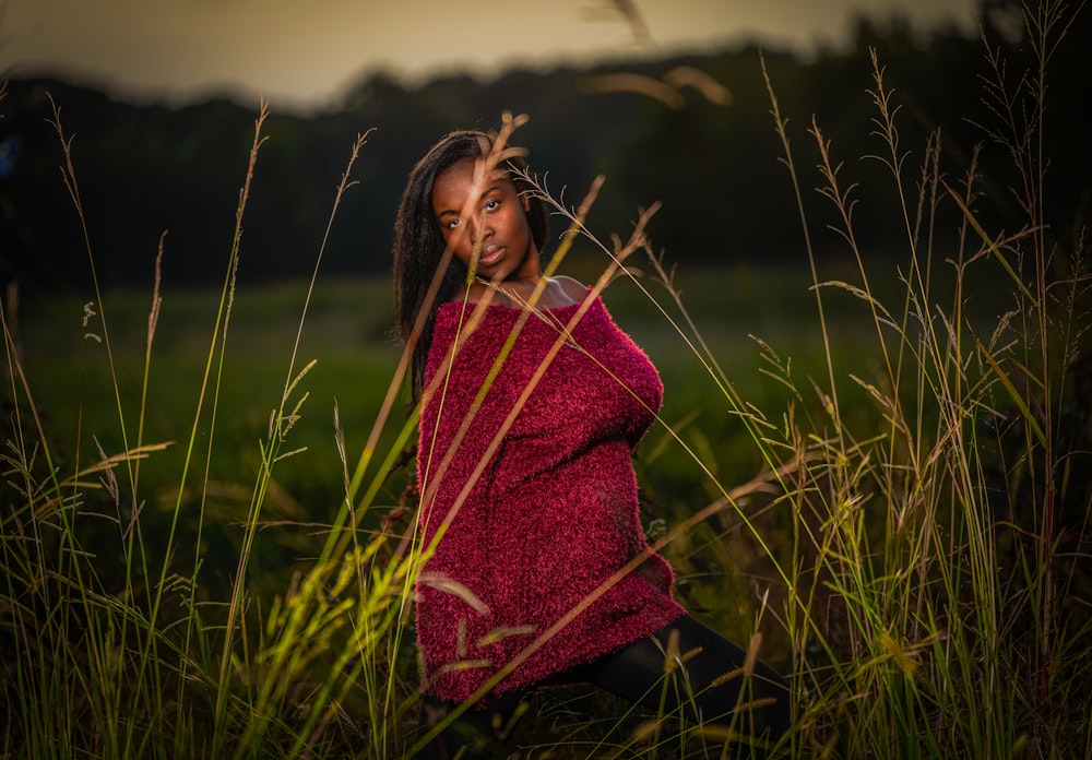 woman in red and black scarf standing on green grass field during daytime