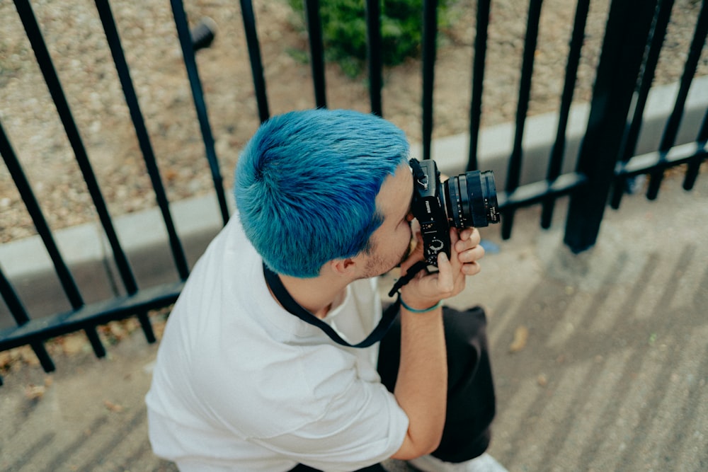 man in white t-shirt holding black dslr camera