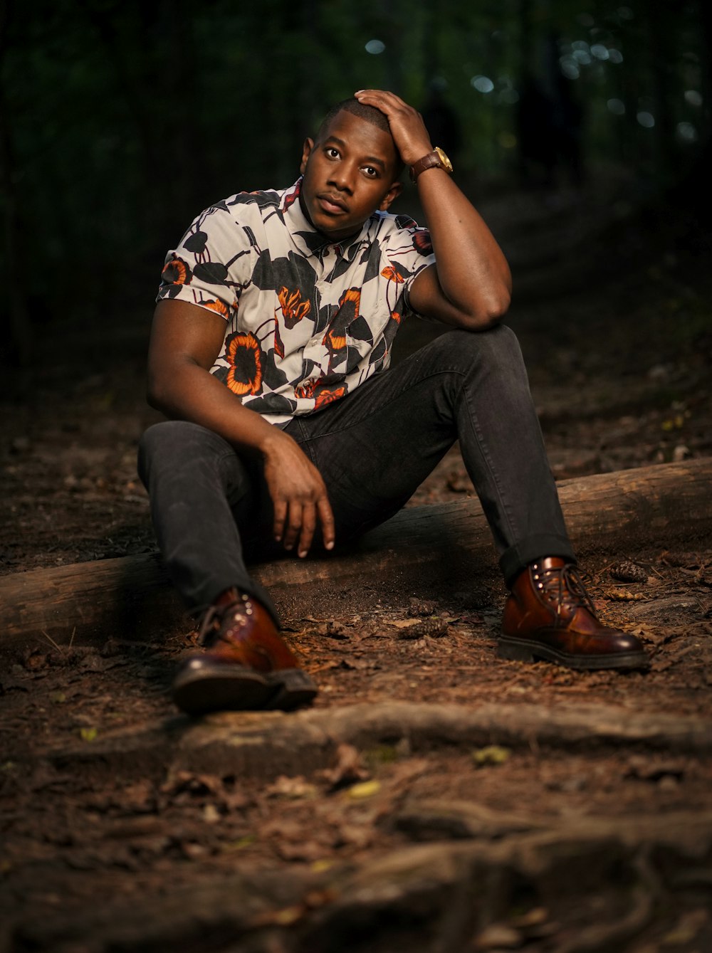 man in white and black crew neck t-shirt and black pants sitting on brown wooden