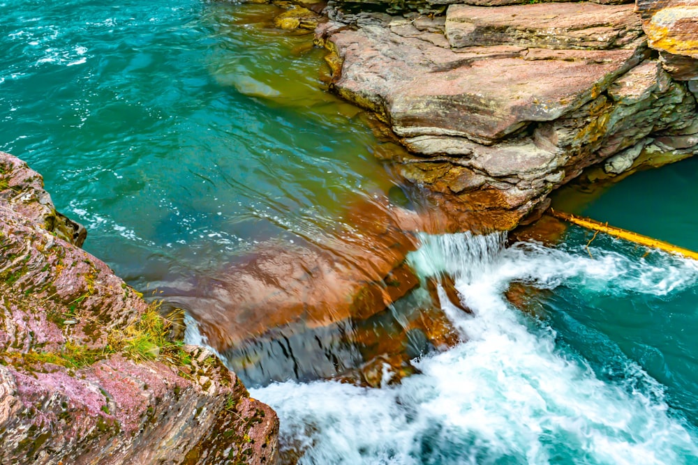 water falls on brown rocky mountain during daytime