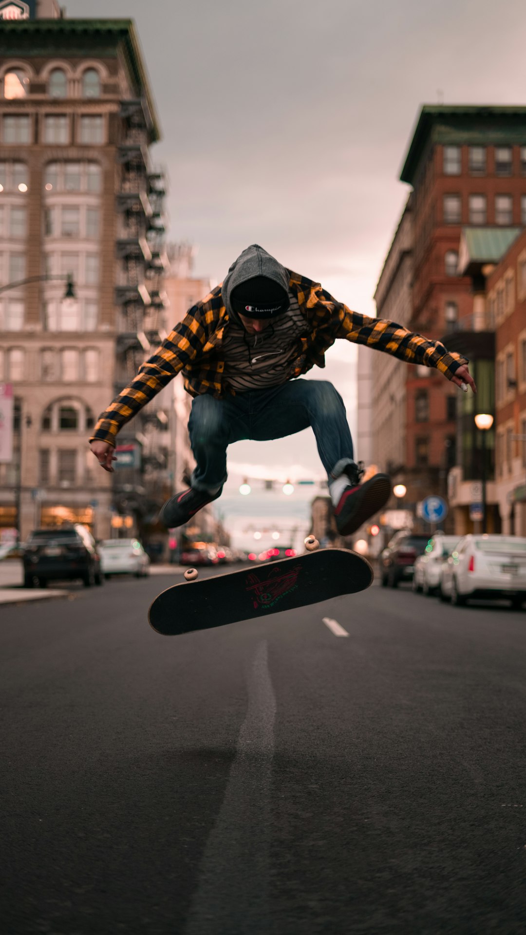 man in black and white jacket and blue denim jeans riding red skateboard during daytime