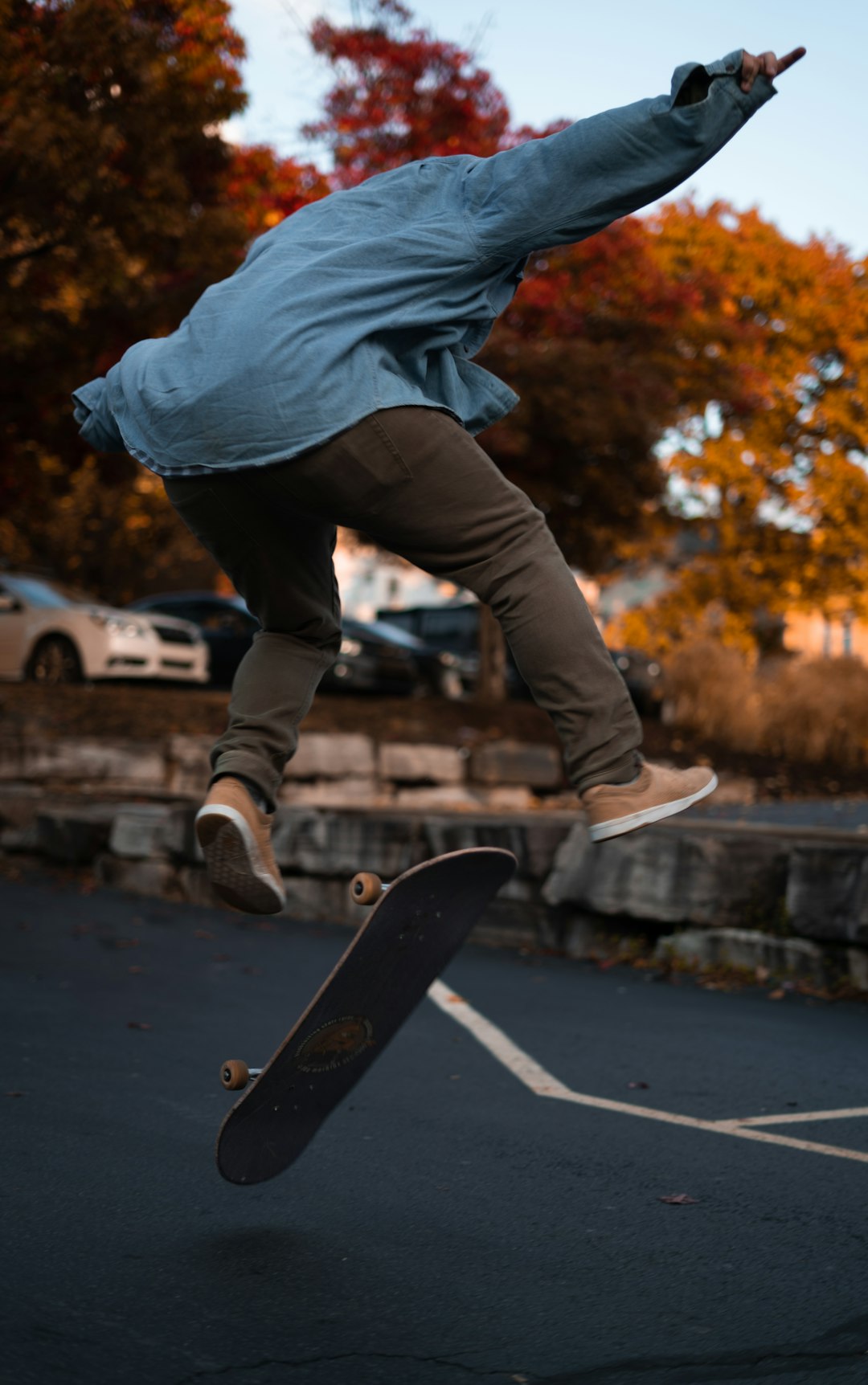 person in gray jacket and black pants wearing black nike sneakers jumping on gray concrete road