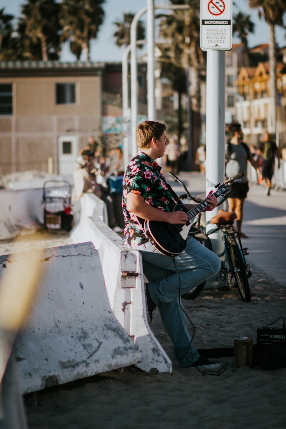 man in black and white floral shirt playing guitar