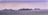 Several cruise ships are sailing on a calm sea beneath an overcast sky. The horizon is visible, with ships positioned from left to right, indicating a procession or fleet at sea.