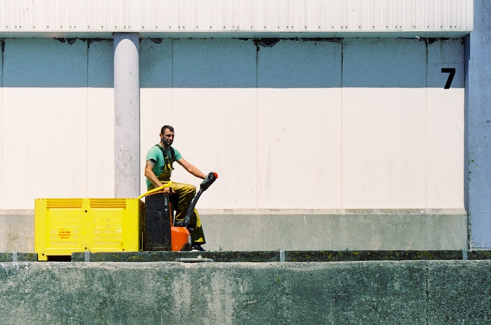 man in black t-shirt and black pants sitting on yellow box