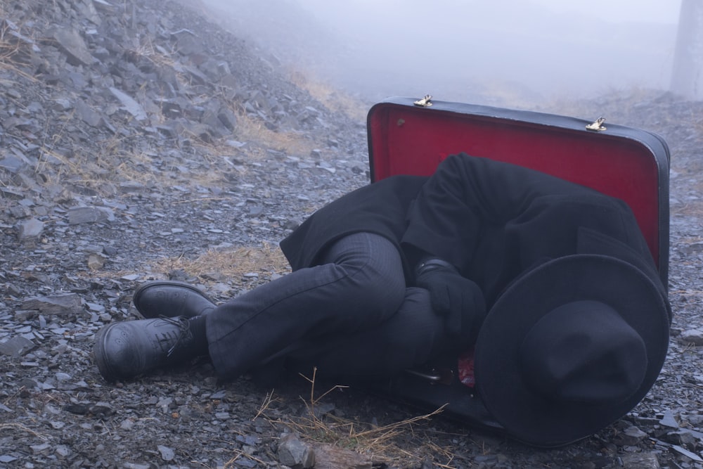 homme en veste noire et pantalon noir assis sur une chaise rouge