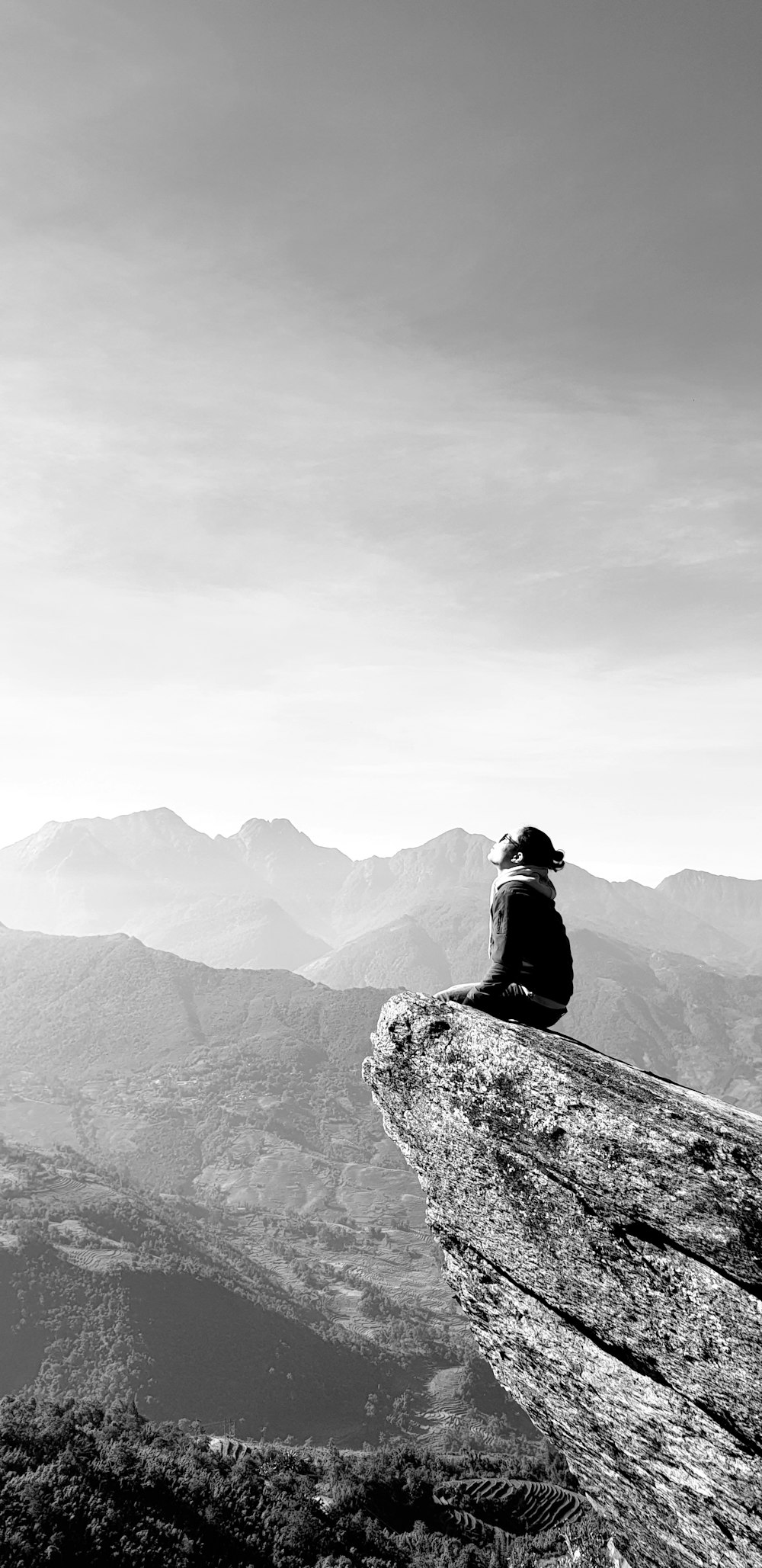 man in black jacket sitting on rock mountain during daytime