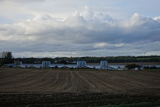 A panoramic view of Corhaven Farms’ expansive fields with tractors working under a cloudy sky.