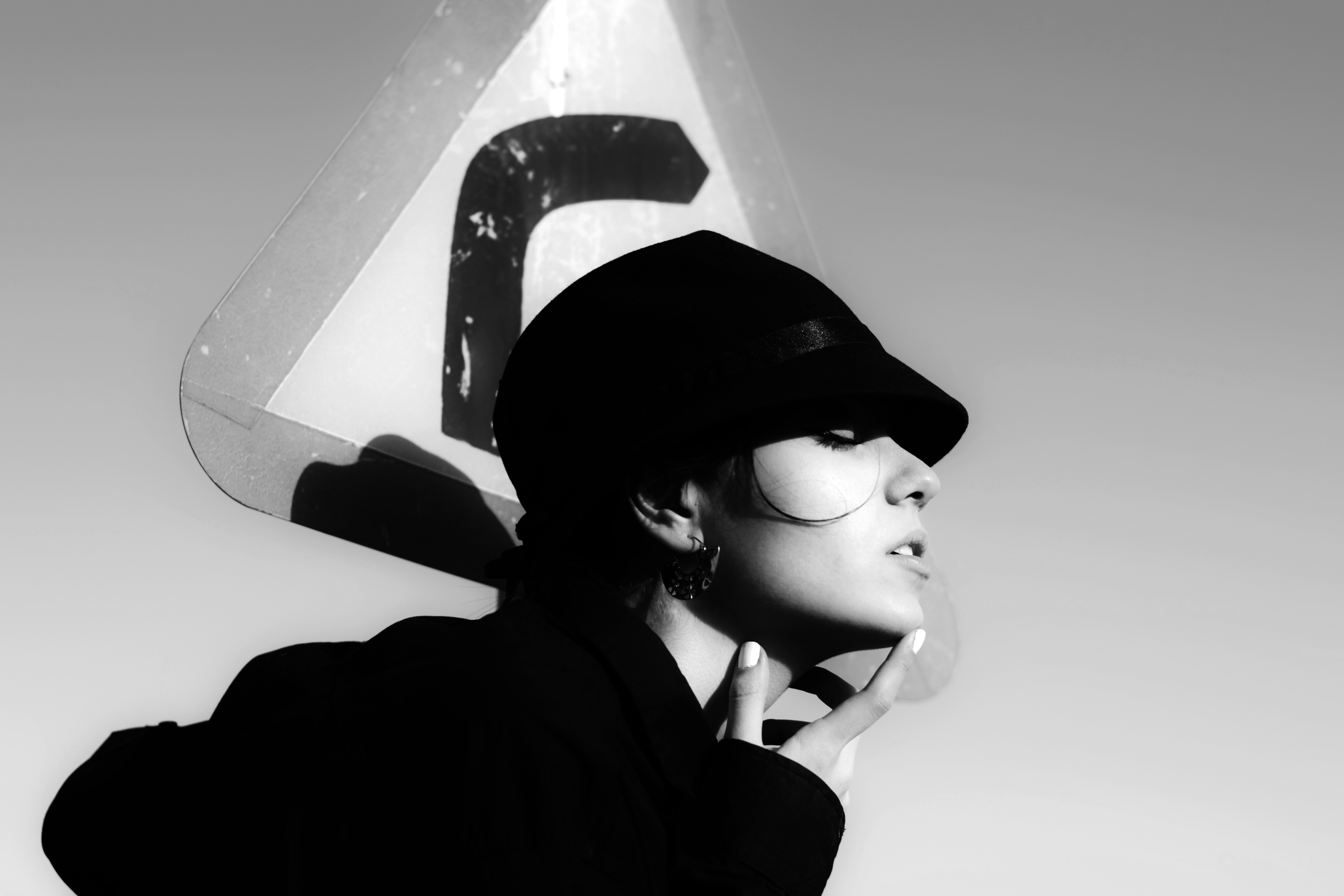 Foto en escala de grises de una mujer con abrigo negro y sombrero negro