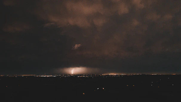 A focused digital sniper scope overlaying a cityscape with storm clouds gathering in the background.