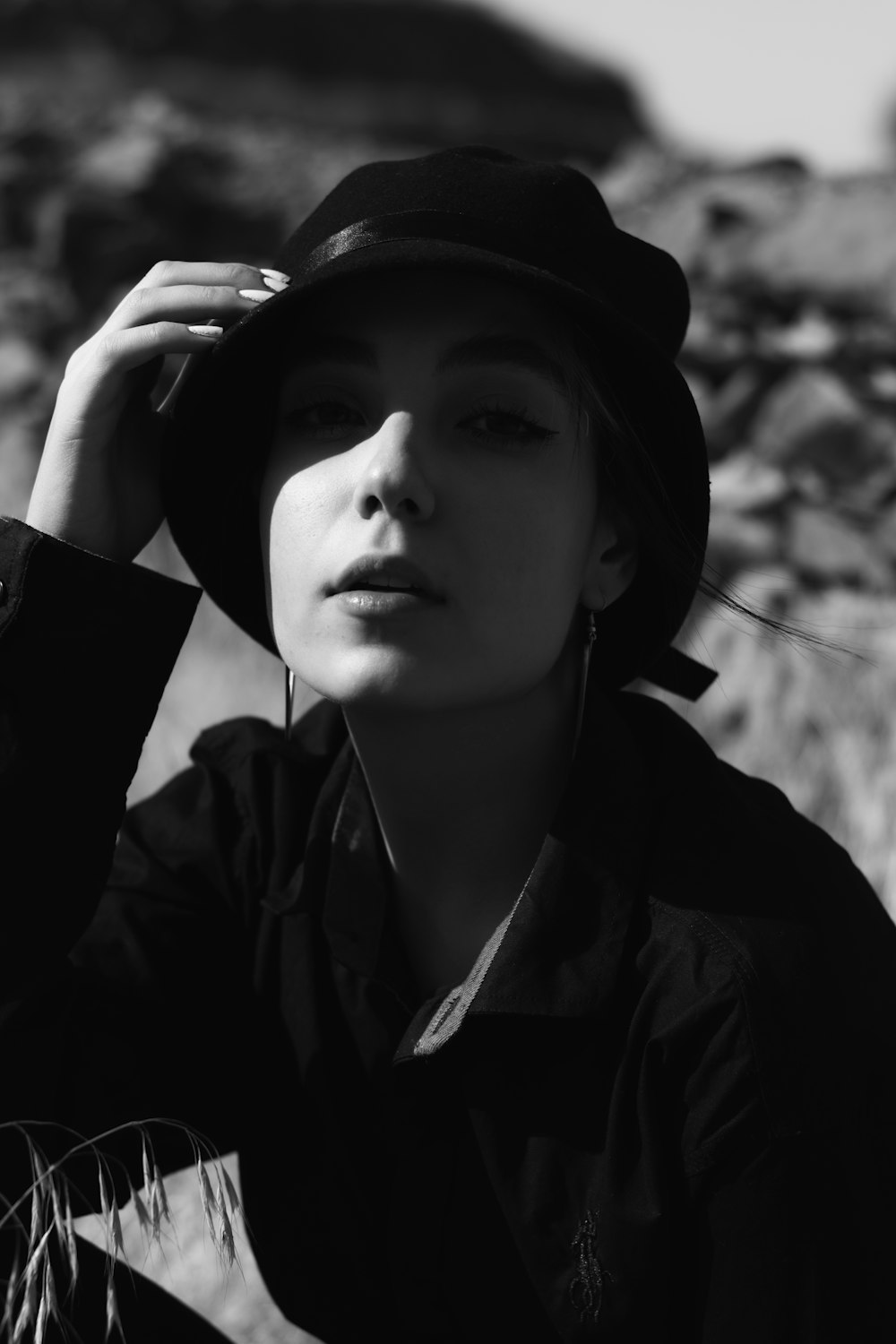 Foto in scala di grigi di donna che indossa cappello e cappotto neri