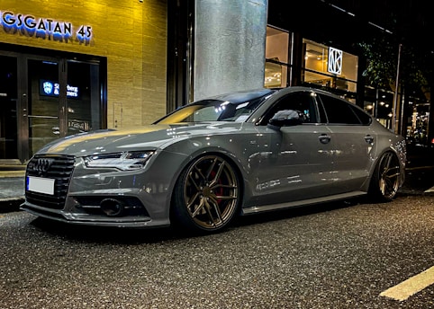 Side view of a sleek car with tinted windows parked on a city street at dusk.