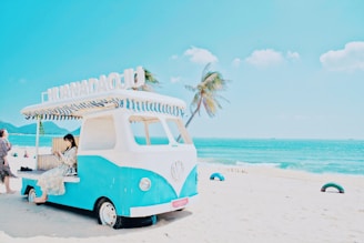 A cheerful traveler using a smartphone on a sunny Curaçao beach to book a rental car online.