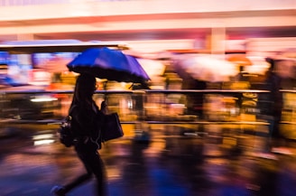 Street photography shot of a rainy city street with reflections and blurred motion of pedestrians.