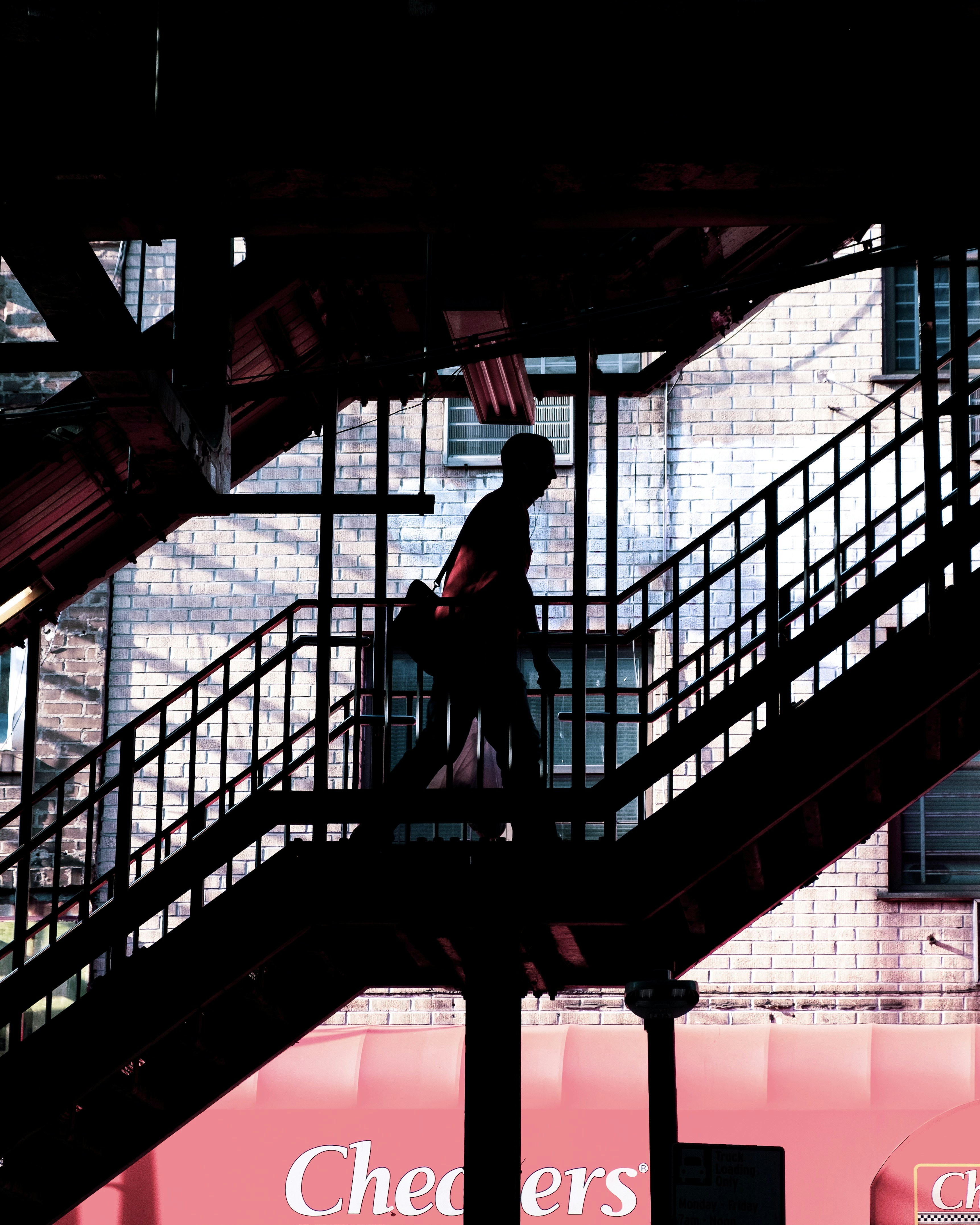 검은 재킷과 바지를 입은 남자가 검은 금속 프레임에 서 있다