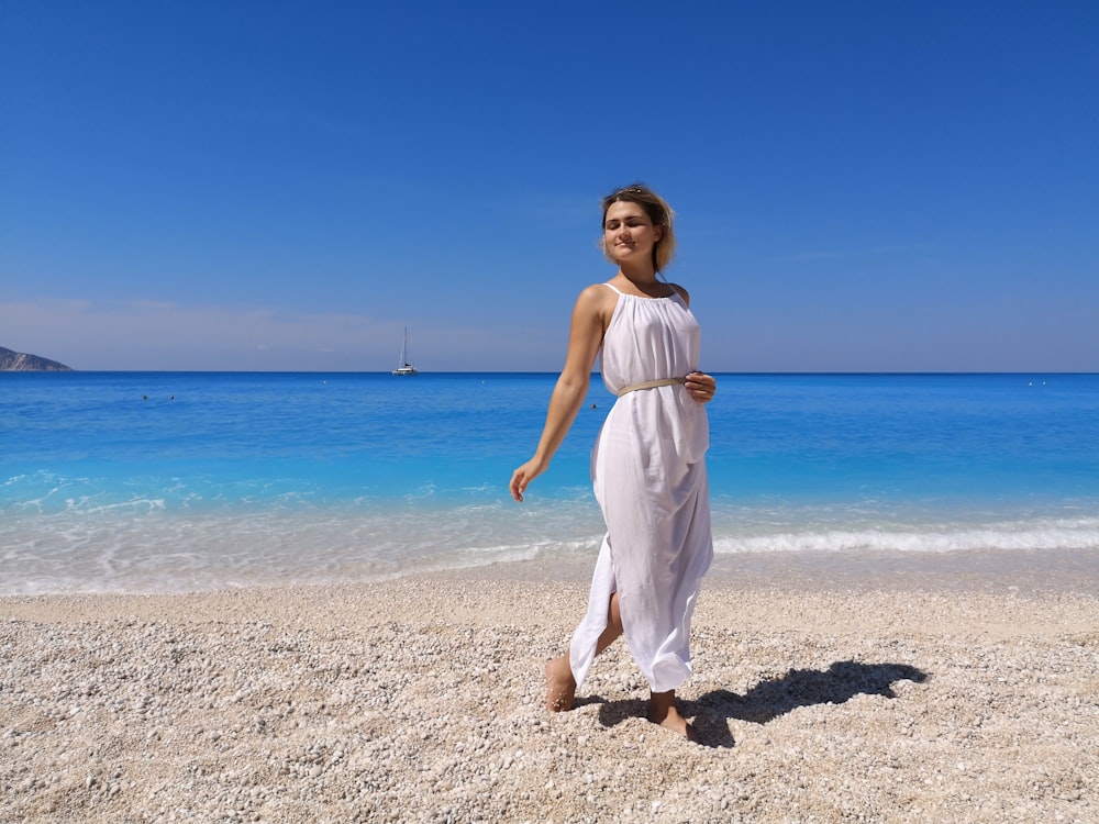 woman in white dress standing on beach during daytime