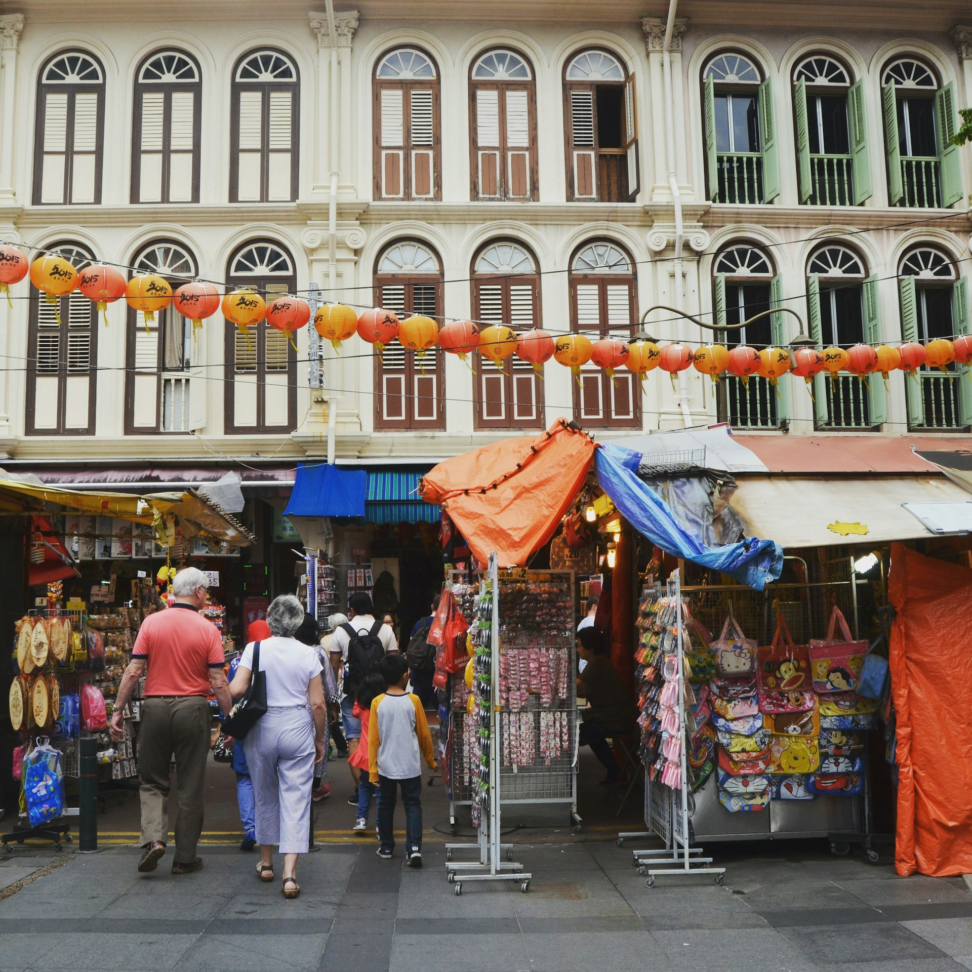 A vibrant street market in Malaysia filled with colorful stalls and local shoppers.