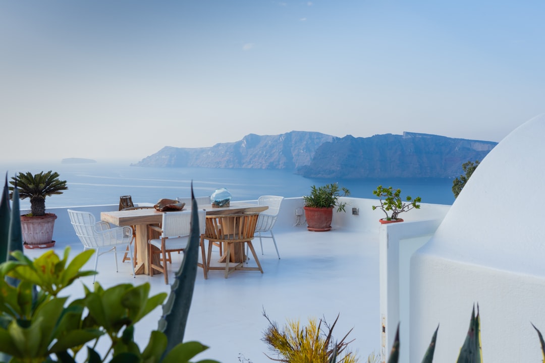 brown wooden table and chairs on white concrete floor, Santorini Lifestyle in Greece @pj_visual