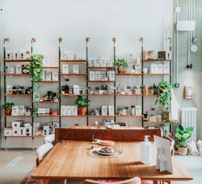 A sleek, modern office breakroom shelf neatly stocked with coffee pods, snacks, and beverages under soft warm lighting.
