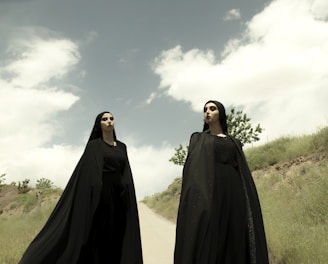 man in black robe standing under white clouds during daytime