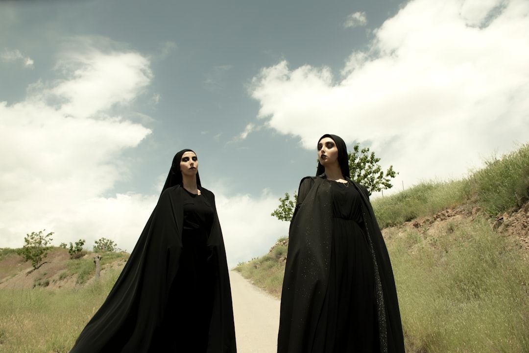 man in black robe standing under white clouds during daytime