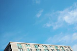 A modern apartment building with clean lines and large windows under a bright blue sky.