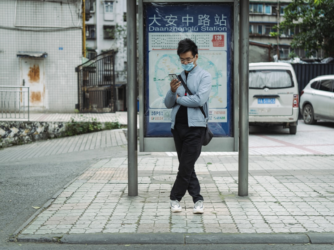 man in blue dress shirt and black pants standing on sidewalk during daytime