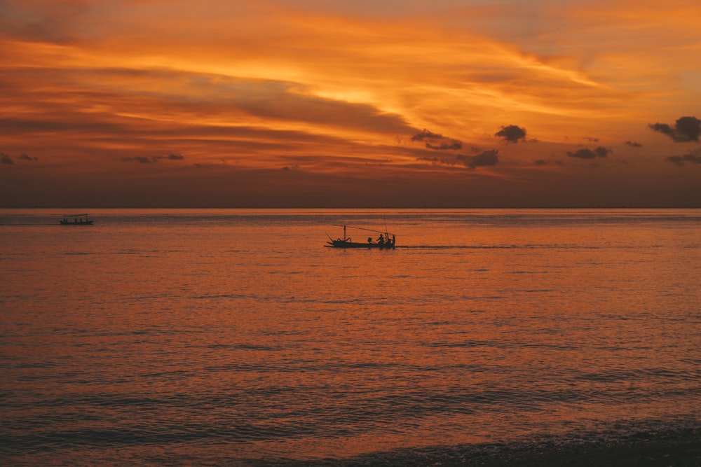 silhouette of boat on sea during sunset