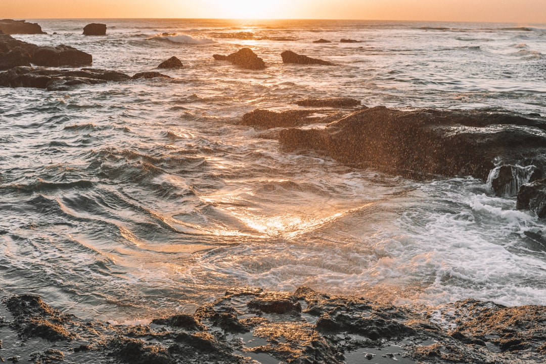 ocean waves crashing on shore during sunset