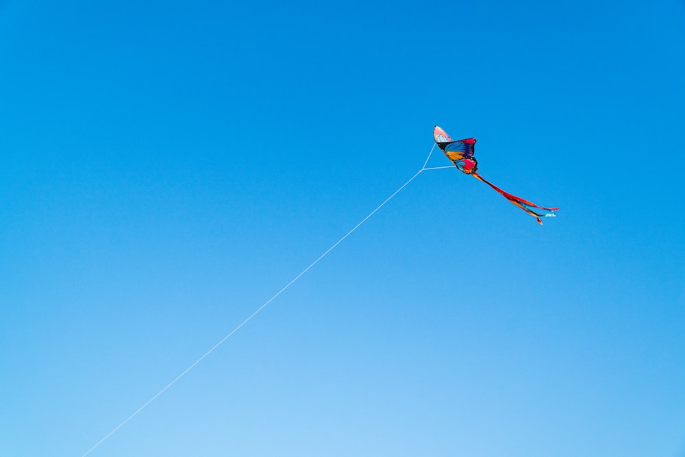 red kite flying on blue sky during daytime