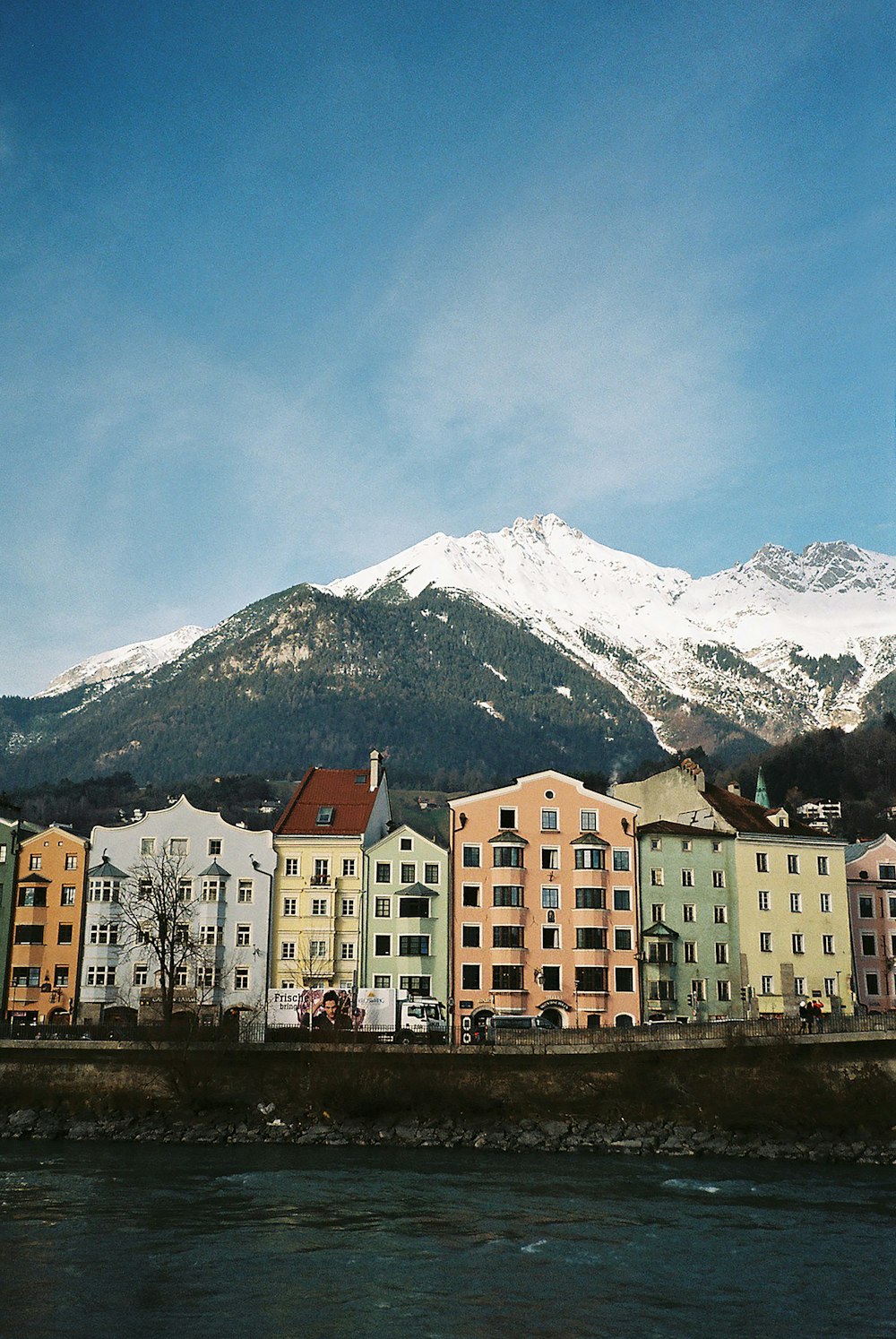 Weiße und braune Betongebäude in der Nähe von schneebedeckten Bergen tagsüber