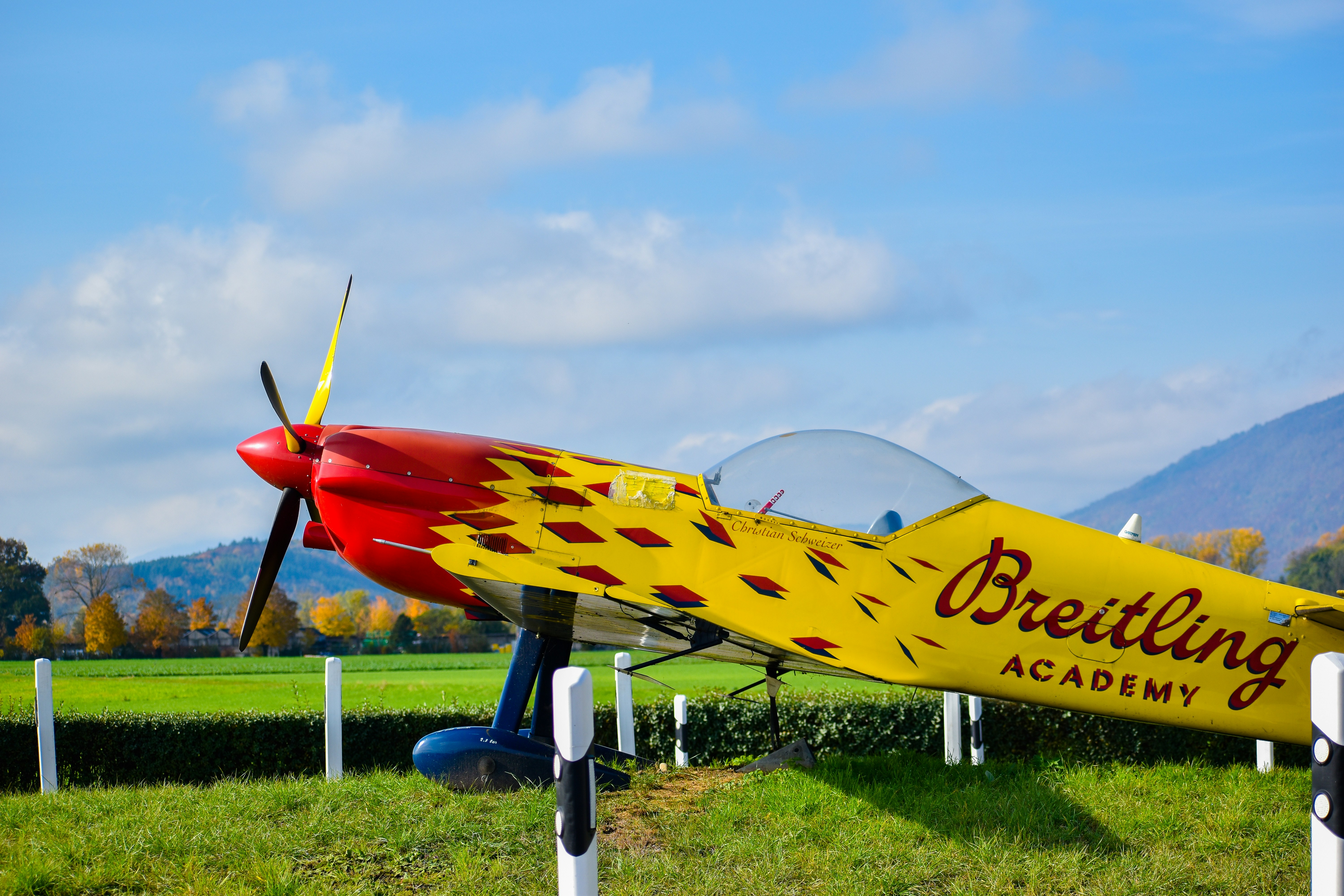 blue and yellow jet plane on green grass field under white clouds and blue sky during