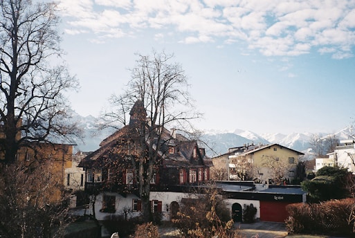 A peaceful village scene in Nagari Sitombol with traditional houses and lush greenery under a clear sky.
