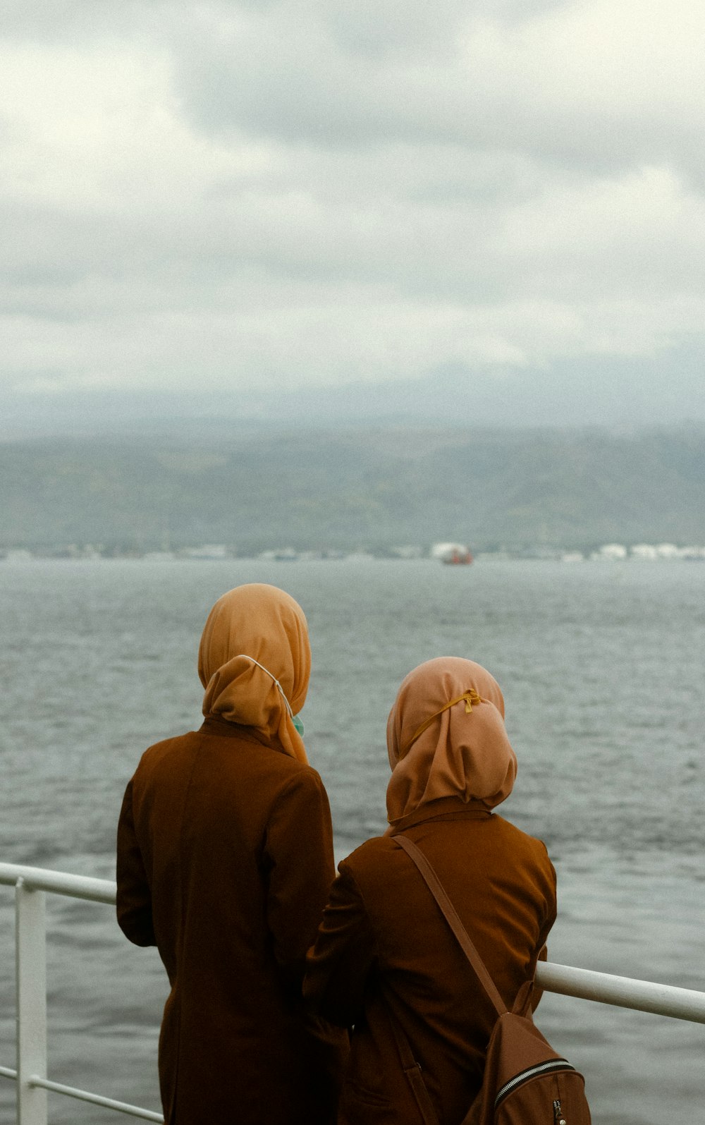 person in brown hoodie standing near body of water during daytime