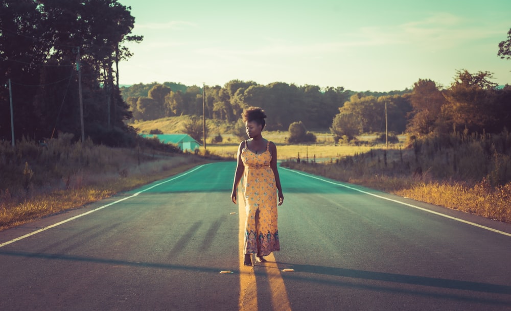 Mujer vestida de marrón parada en la carretera durante el día