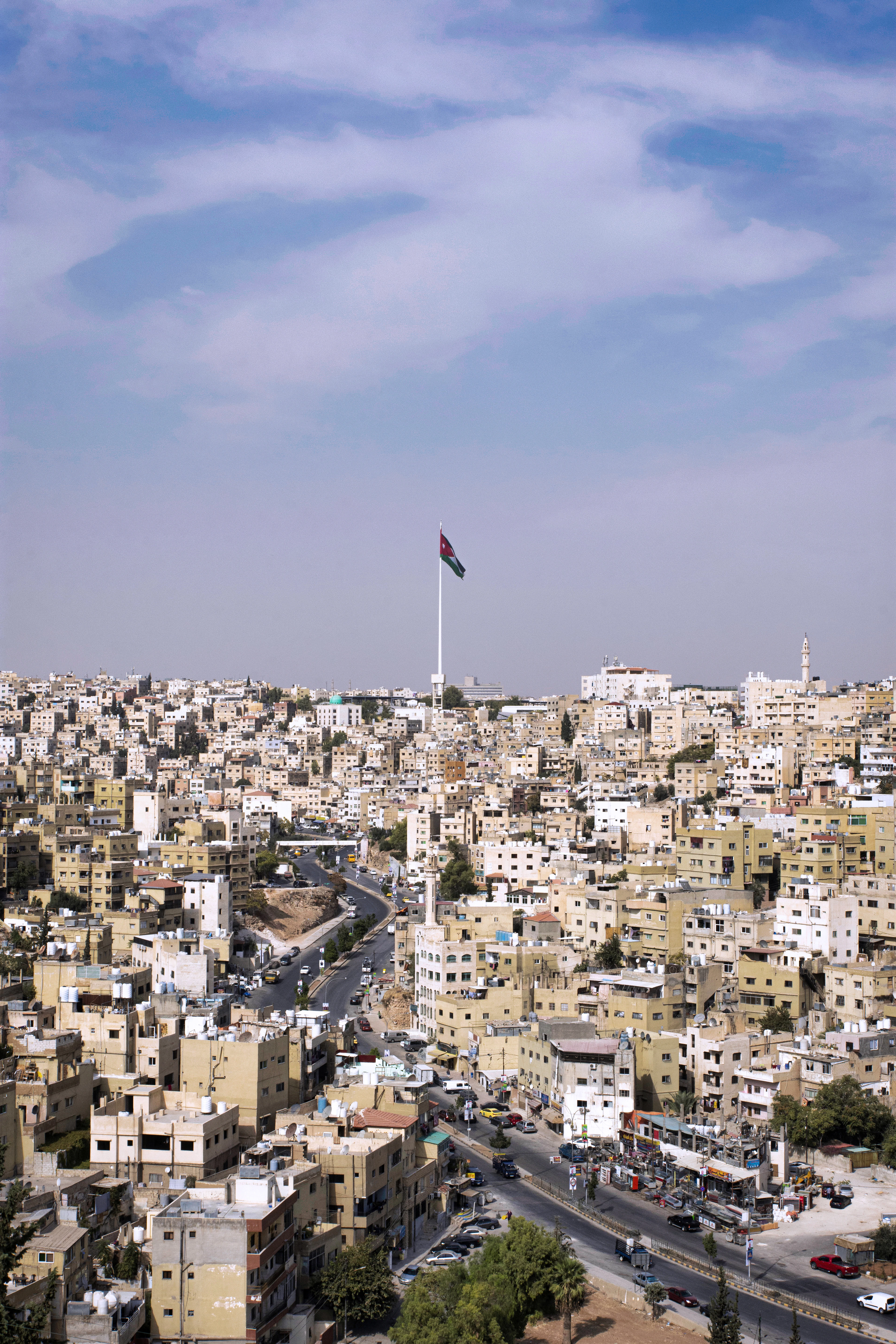 Jordan's flag flies atop a tall pole over Amman's dense hillside of cream-colored apartment buildings.