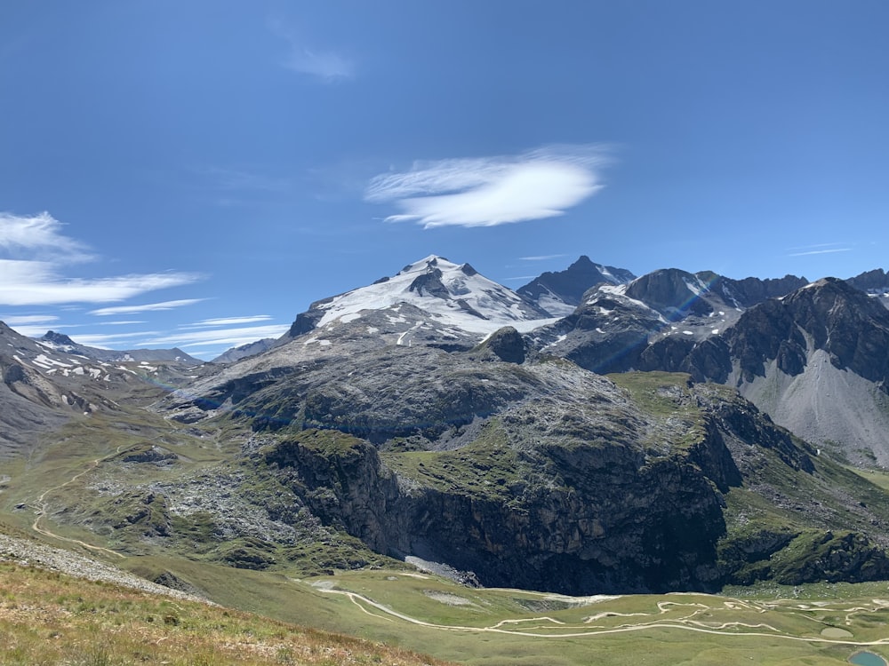 green grass field and mountain under blue sky during daytime