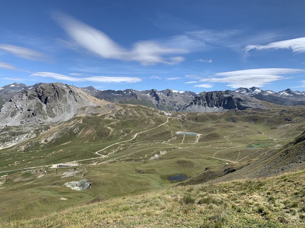 green grass field and mountains under blue sky during daytime