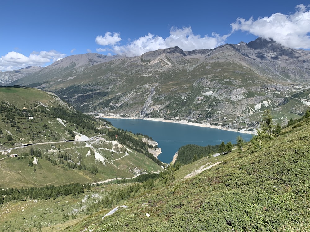 montagnes vertes et blanches près du plan d’eau sous le ciel bleu pendant la journée