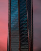 A sleek downtown commercial building with reflective glass windows at sunset.