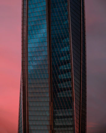 A sleek, modern glass building with golden accents reflecting the sunset, symbolizing premium real estate.