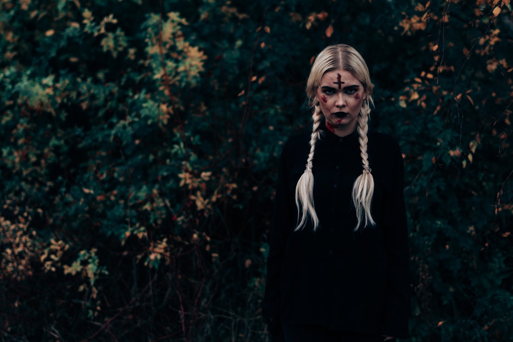 woman in black long sleeve shirt standing near green trees during daytime