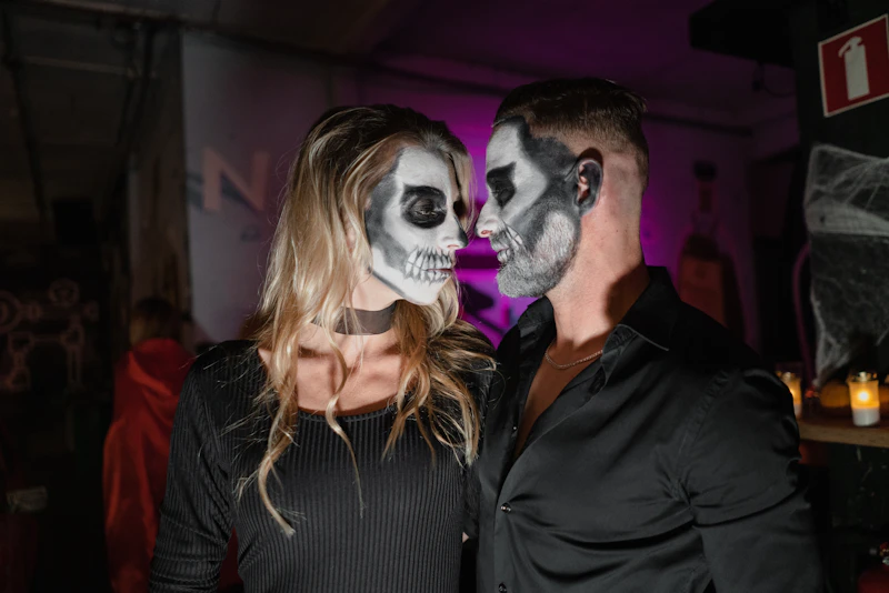 homme en chemise noire à côté d'une femme en masque blanc
