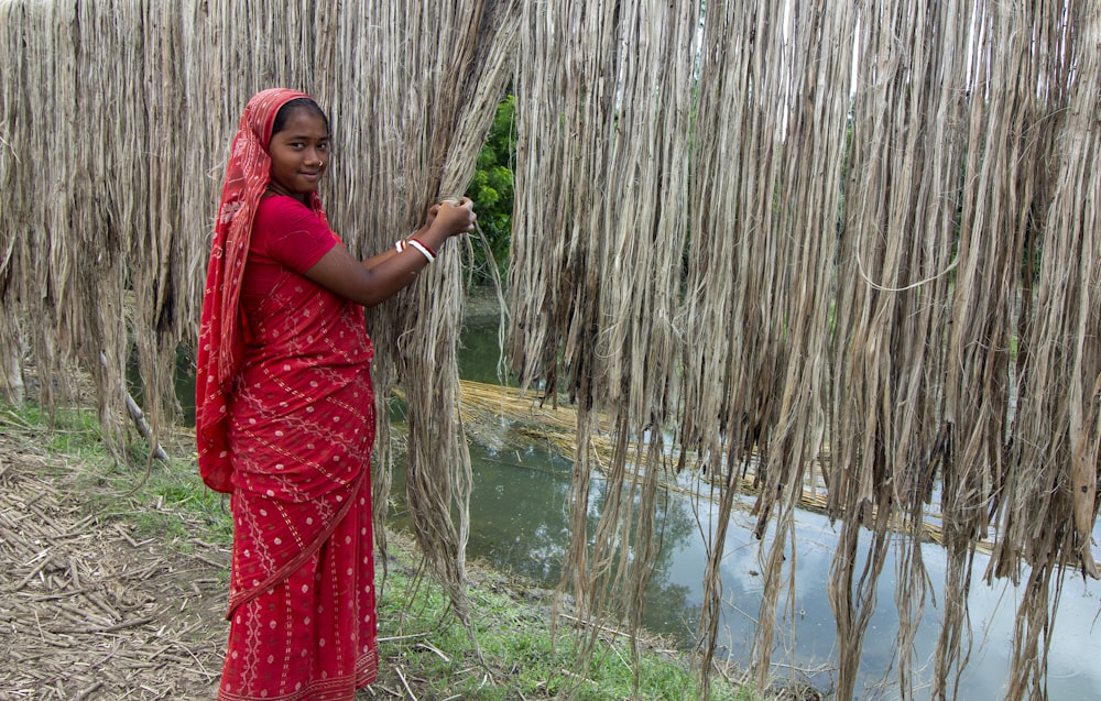 woman in red hijab standing near brown bamboo tree during daytime