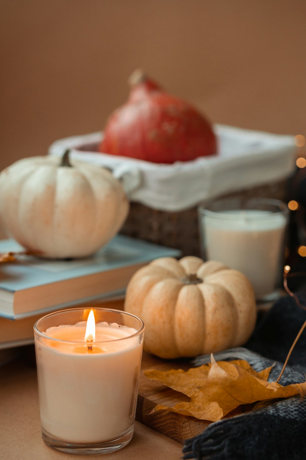 white and red round fruit beside white pillar candle on brown wooden table