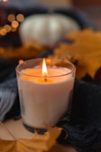 A close-up of a candle decorated with autumn leaves.