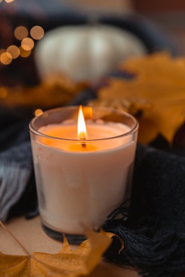 A close-up of a candle decorated with autumn leaves.