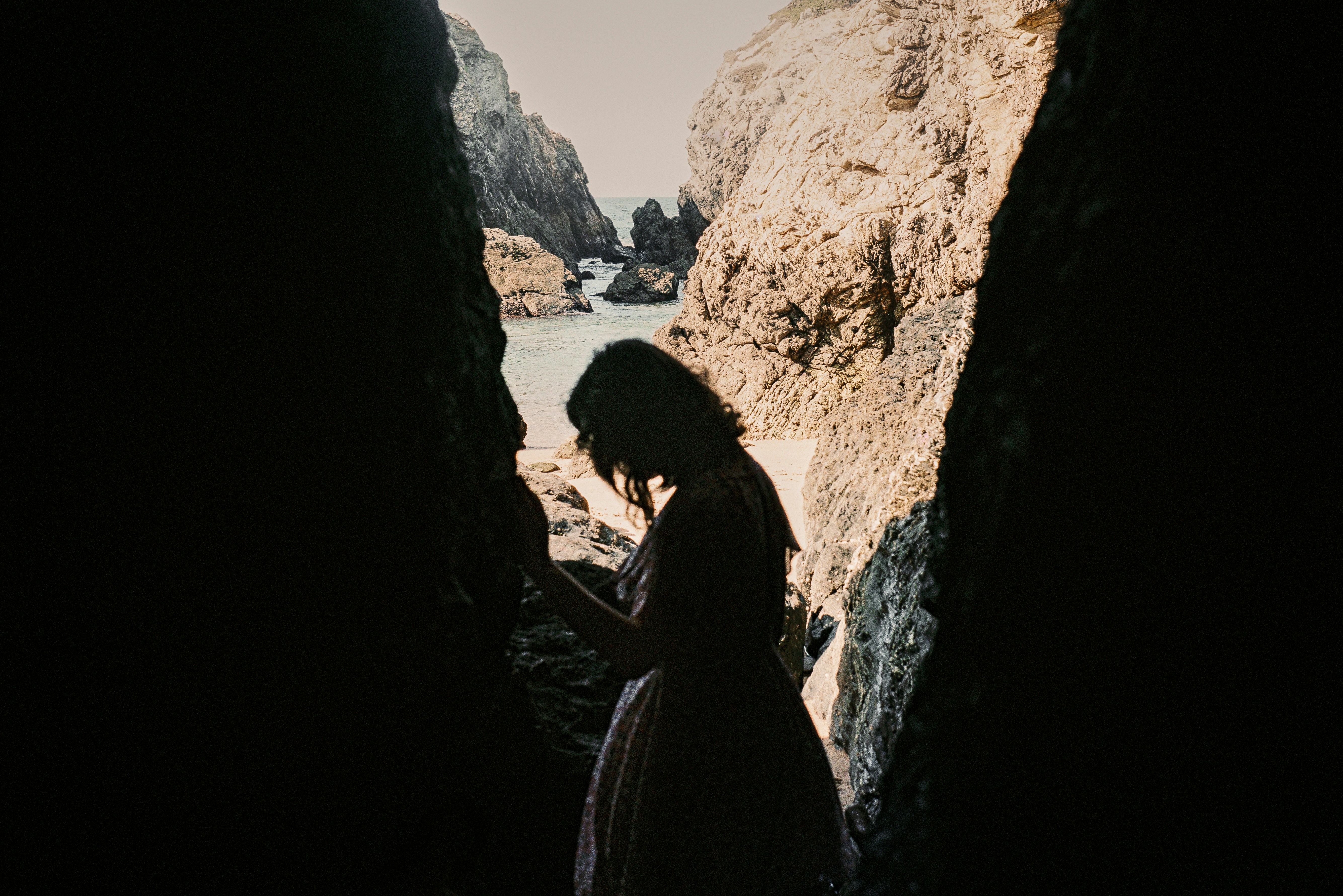 woman in black dress standing on rock formation during daytime